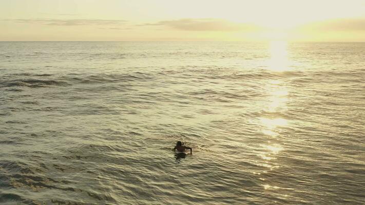 man-on-surfboard-waiting-for-wave-in-the-sea-at-sunset-video